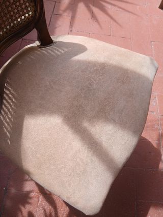 Silla antigua de madera con asiento tapizado.