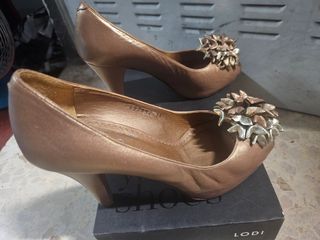 Zapatos de tacón dorados con flor.