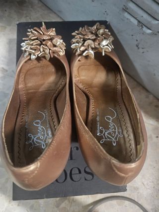 Zapatos de tacón dorados con flor.