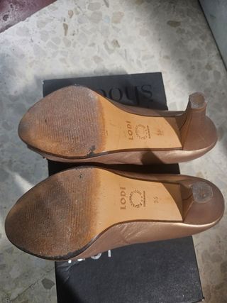 Zapatos de tacón dorados con flor.