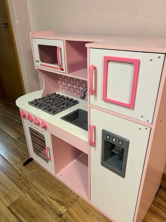 Cocinita de madera rosa y blanca.