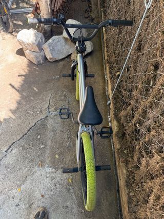 Bicicleta BMX plateada con ruedas verdes