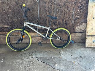 Bicicleta BMX plateada con ruedas verdes