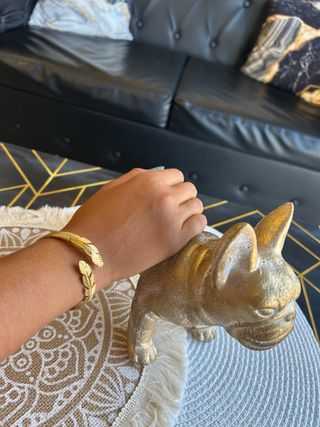 Pulsera dorada con diseño de plumas