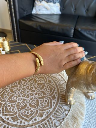 Pulsera dorada con diseño de plumas