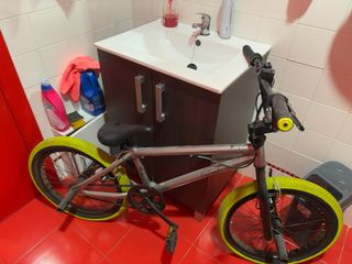 Bicicleta BMX plateada con ruedas amarillas