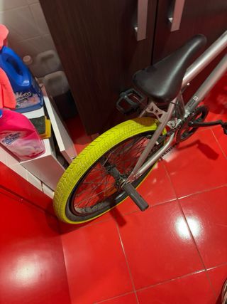 Bicicleta BMX plateada con ruedas amarillas