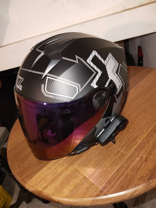 Casco de moto negro con visor morado con auricular
