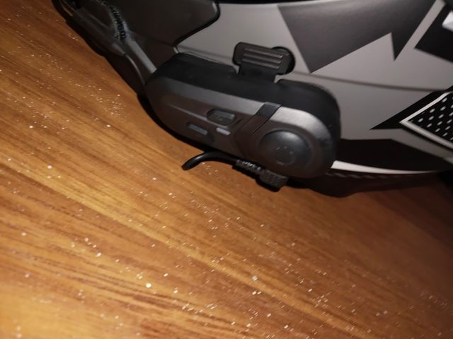 Casco de moto negro con visor morado con auricular