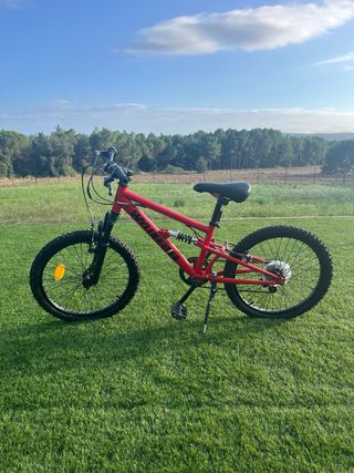 Bicicleta infantil roja de doble suspensión. 