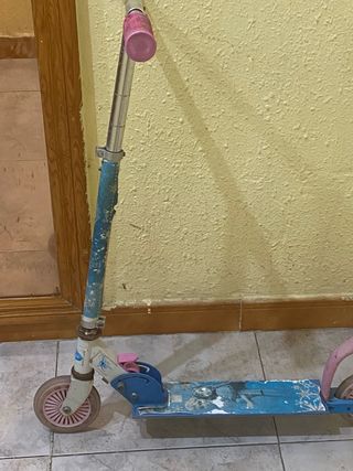 Patinete infantil azul con ruedas rosas.