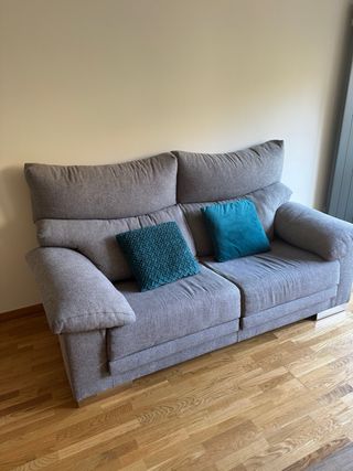 Sofá gris con cojines turquesa.
