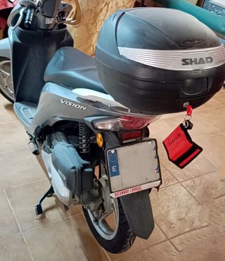 Honda Vision 110 gris con baúl.