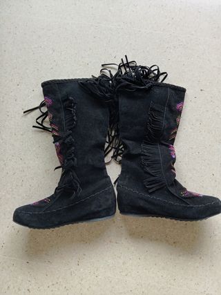 Botas altas ante negras bordadas con flecos.