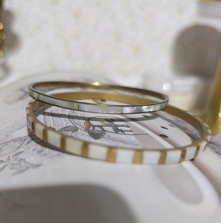 Dos pulseras rígidas doradas con nácar