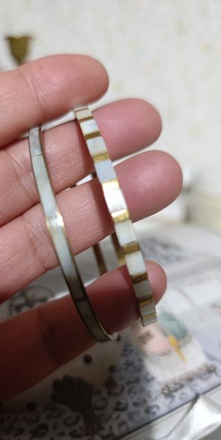 Dos pulseras rígidas doradas con nácar