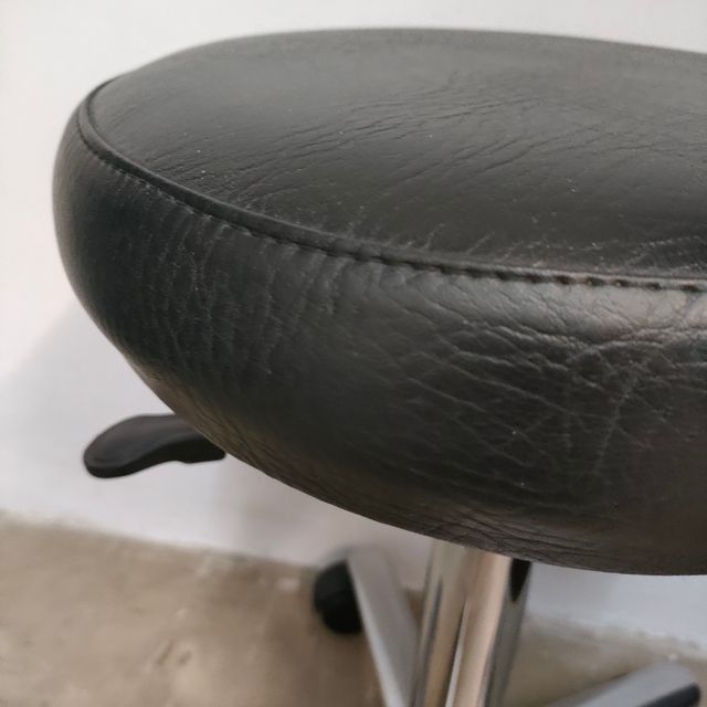 Taburete médico con ruedas y altura regulable.