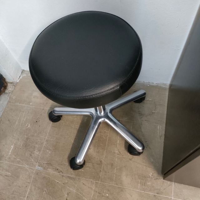 Taburete médico con ruedas y altura regulable.