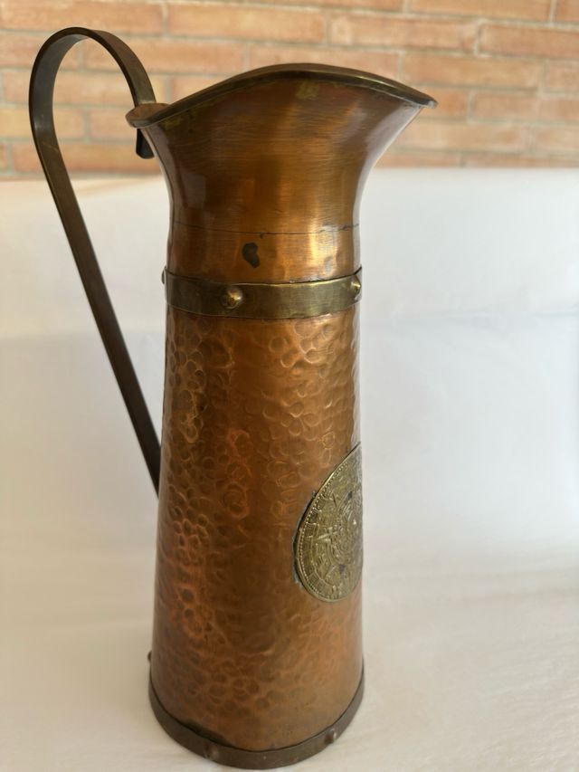 Jarra de metal con diseño azteca