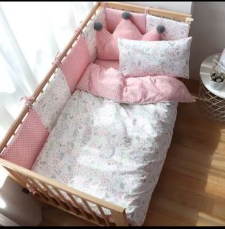 Cuna de madera con colchón, protectores y edredón.
