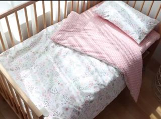 Cuna de madera con colchón, protectores y edredón.