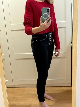 Pantalón vaquero negro y suéter rojo