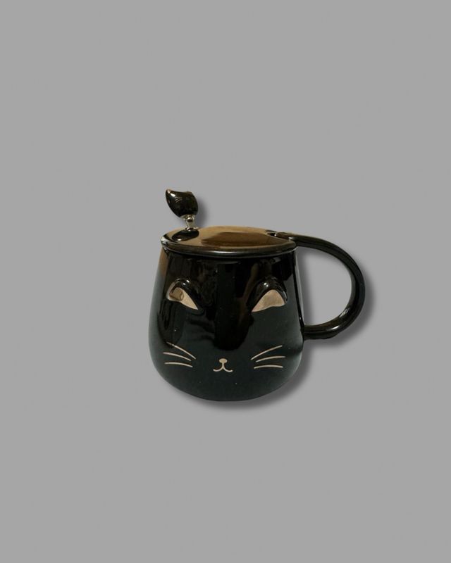 Taza negra con tapa y cuchara de gato.