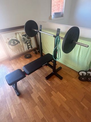 Press banca reclinable con barra y discos.