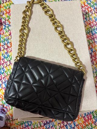 Bolso negro con cadena dorada de Zara.