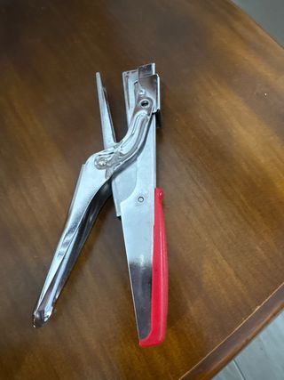 Grapadora de metal plateada con mango rojo