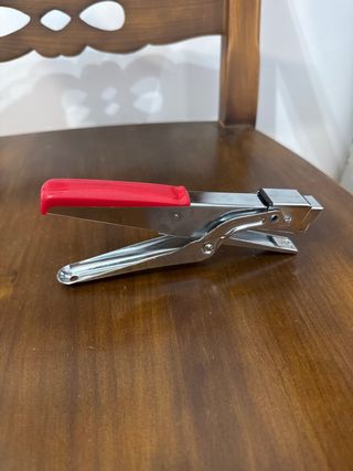 Grapadora de metal plateada con mango rojo