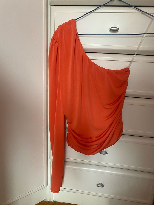 Blusa naranja de un hombro.