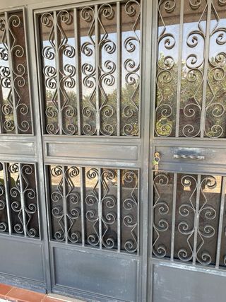 Puerta de hierro y cristal con rejas