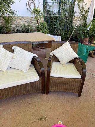 Sofá y sillón de ratán marrón con cojines blancos