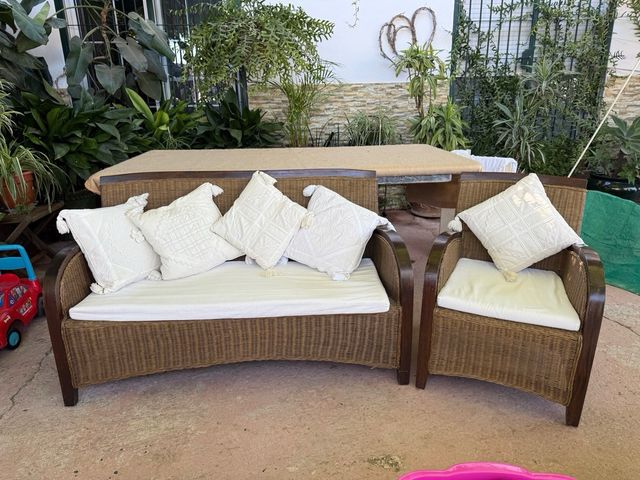 Sofá y sillón de ratán marrón con cojines blancos