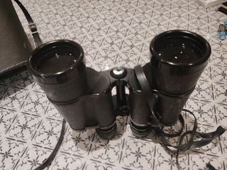 Prismáticos negros con correa y su funda.