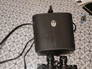 Prismáticos negros con correa y su funda.