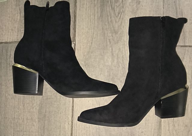 Botines negros con tira en el tacón dorada.