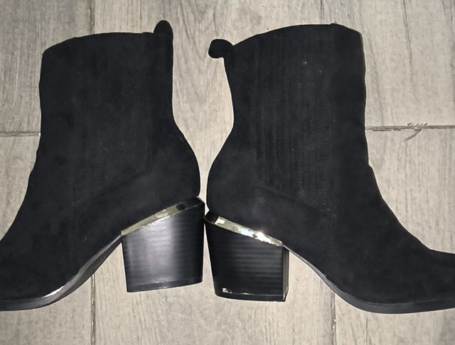 Botines negros con tira en el tacón dorada.