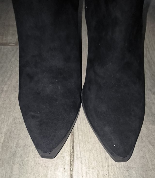 Botines negros con tira en el tacón dorada.