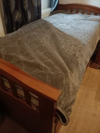 Cama de madera con manta gris