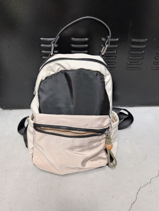Mochila pequeña beige y negra de nylon.