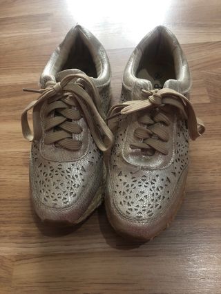 Zapatos dorados con cordones y diseño troquelado