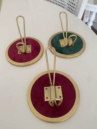 Percheros de pared dorados con base de terciopelo 