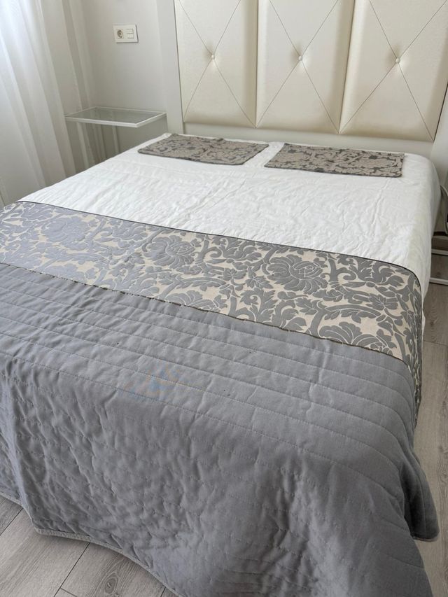 Colcha y fundas de tela grises y blancas