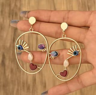 Pendientes dorados con diseño de rostro arte