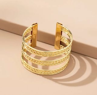 Brazalete dorado abierto con diseño trenzado