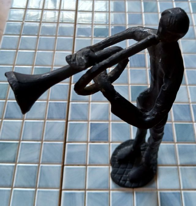 Escultura de metal de músico con trompeta