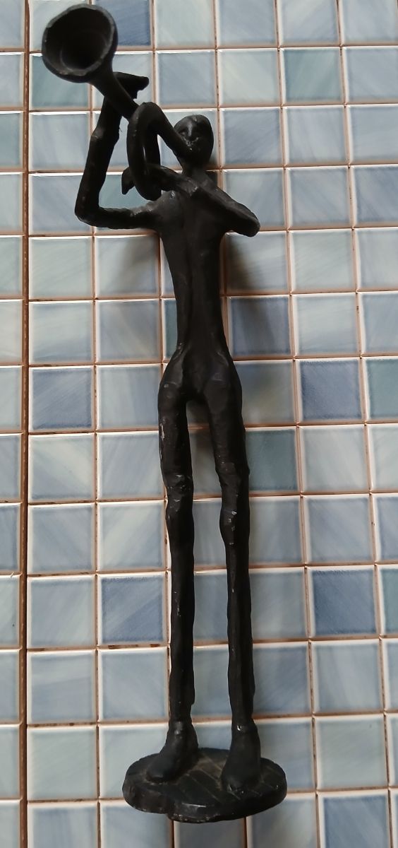 Escultura de metal de músico con trompeta