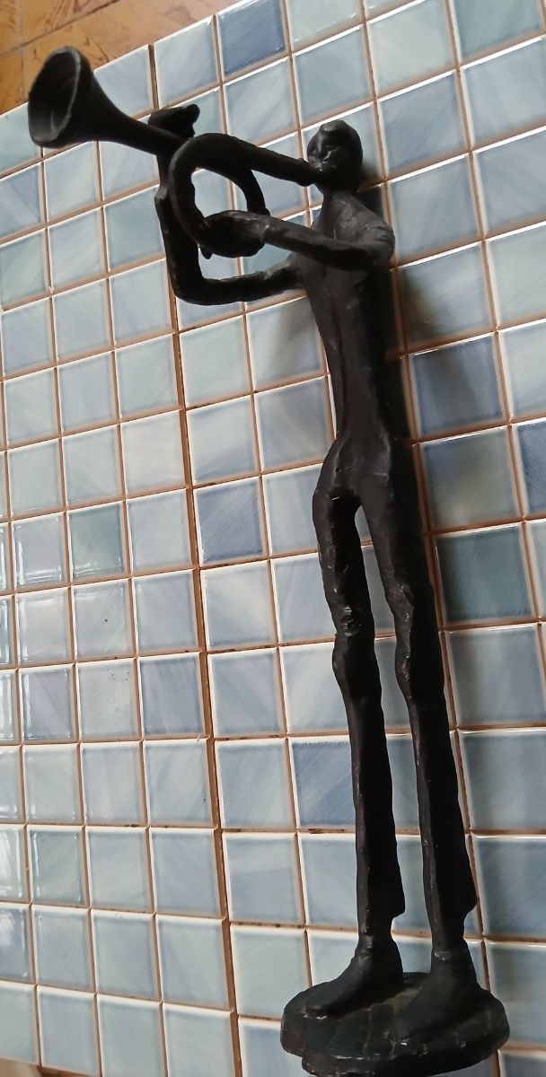 Escultura de metal de músico con trompeta